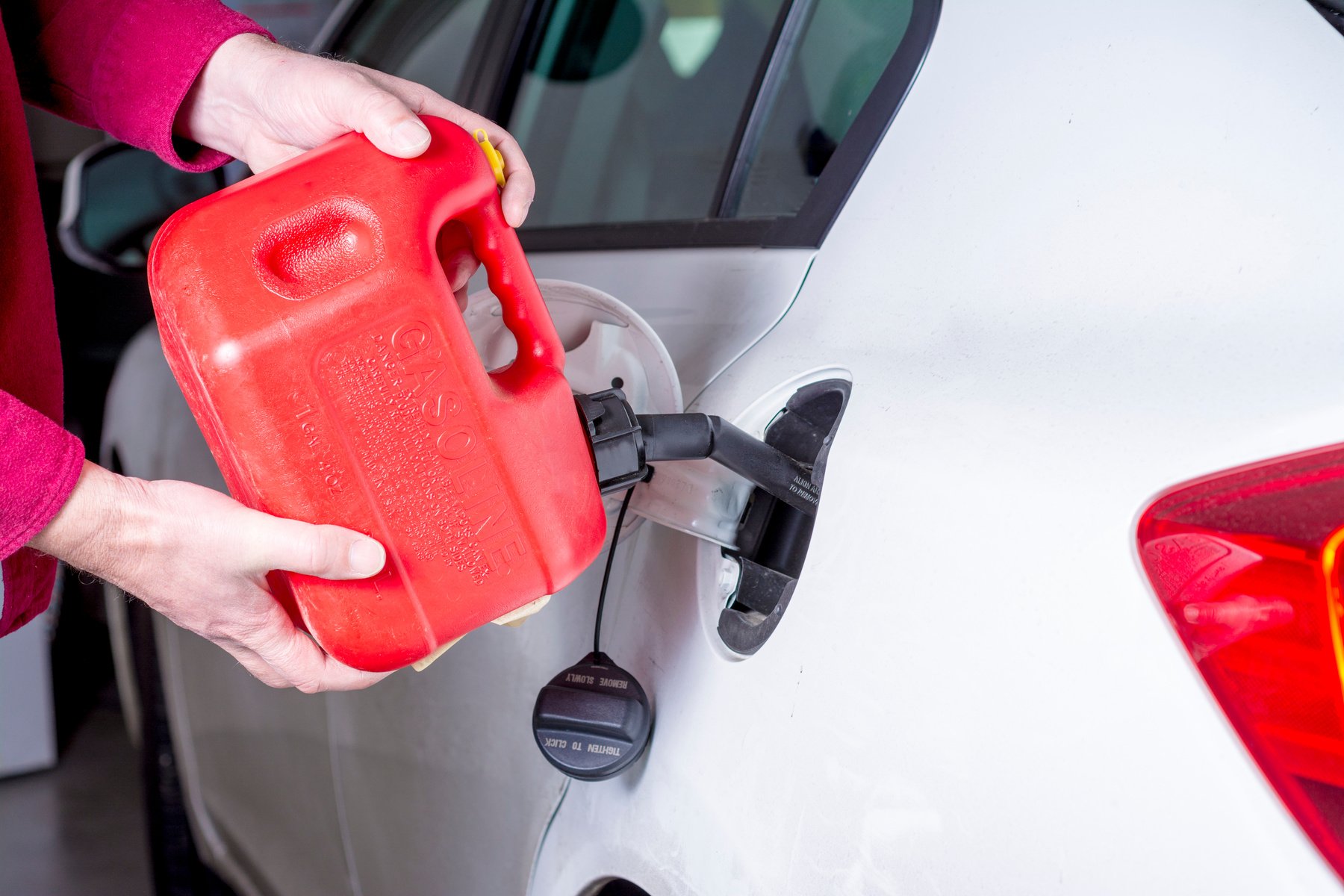 Red gas can adds fuel to an automobile